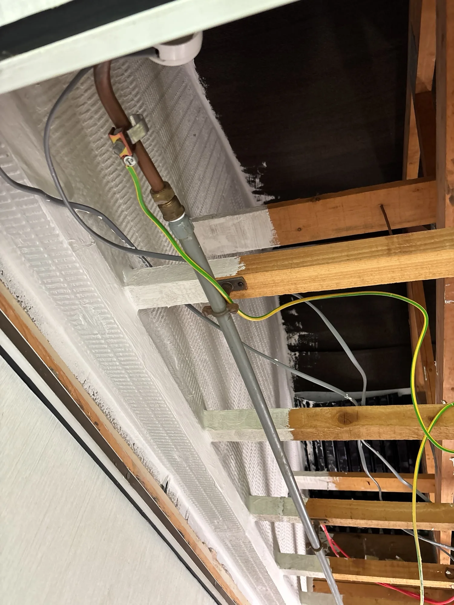 Fire protection installation in attic space with visible services and insulation