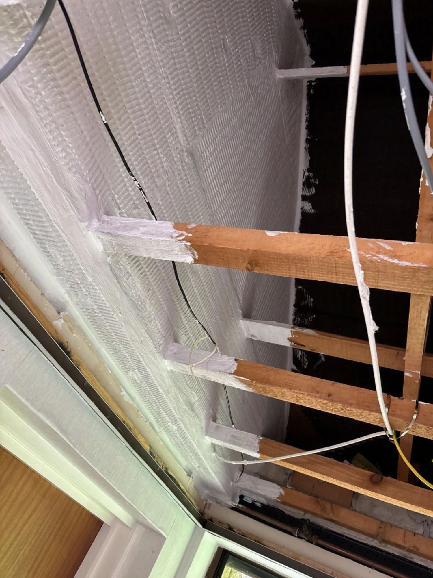 Installation of fire barrier with visible wooden beams and electrical wiring