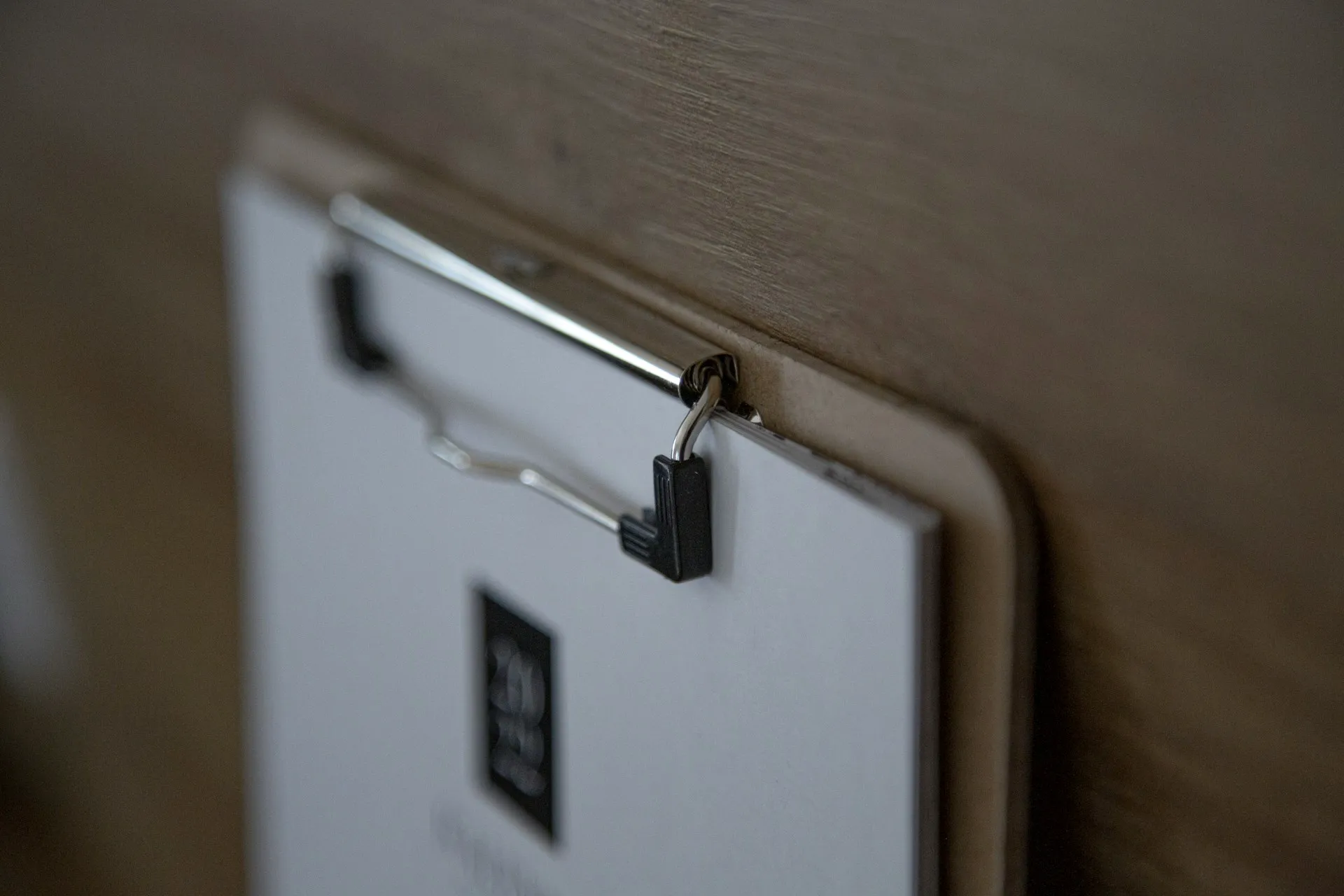 A close-up of a clipboard clip holding a white document against a wooden background