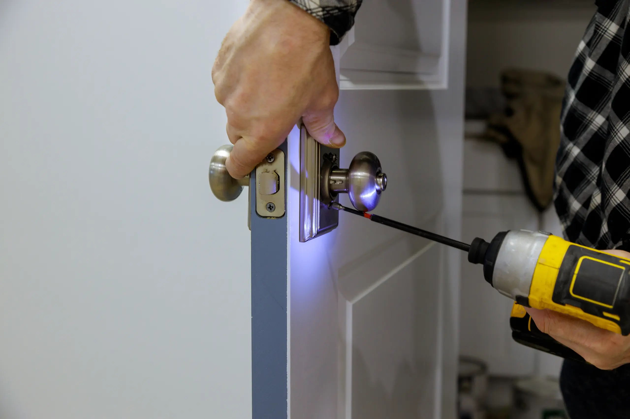Installing a fire door handle with a screwdriver and flashlight for fire safety