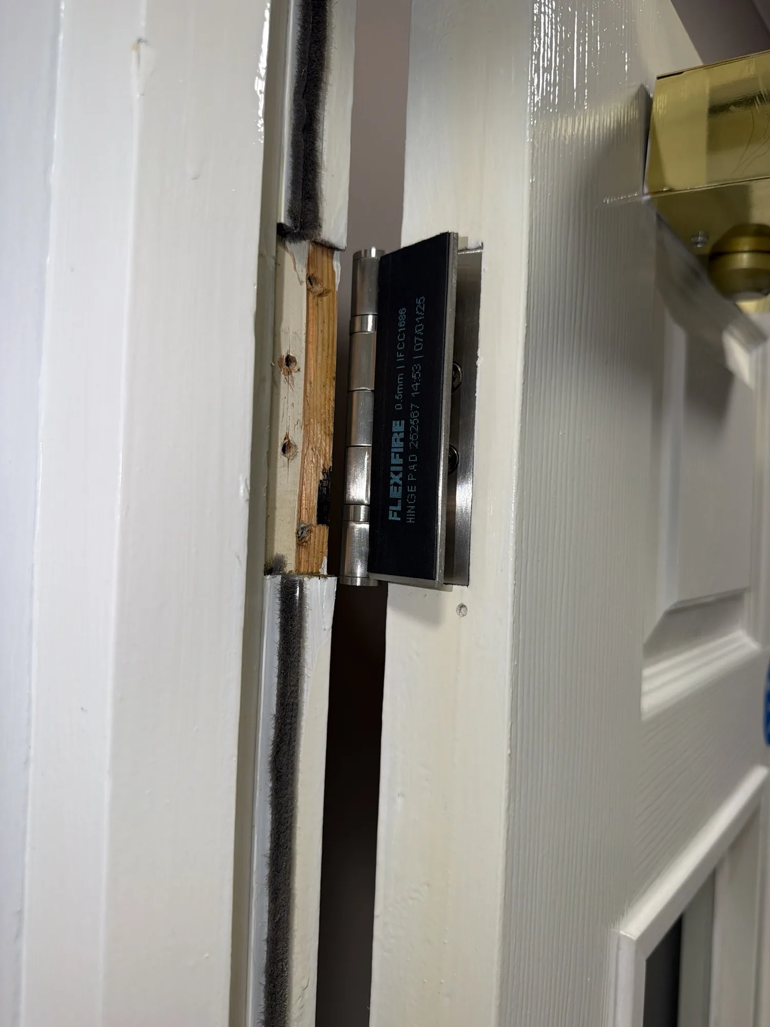 Close-up of a fire door hinge with a fire safety certification label