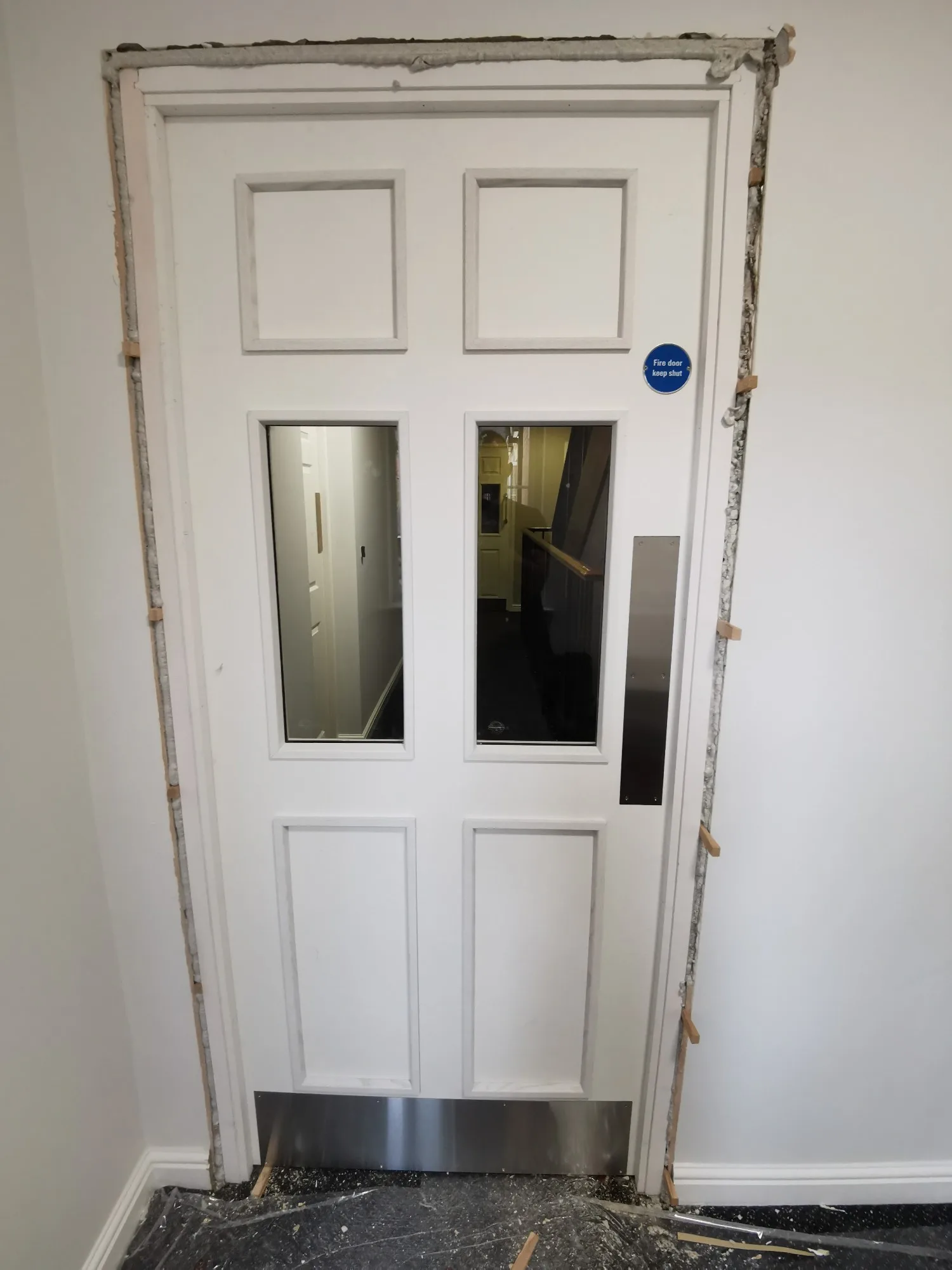 Fire door installation with visible frame and access panel, under preparation for completion