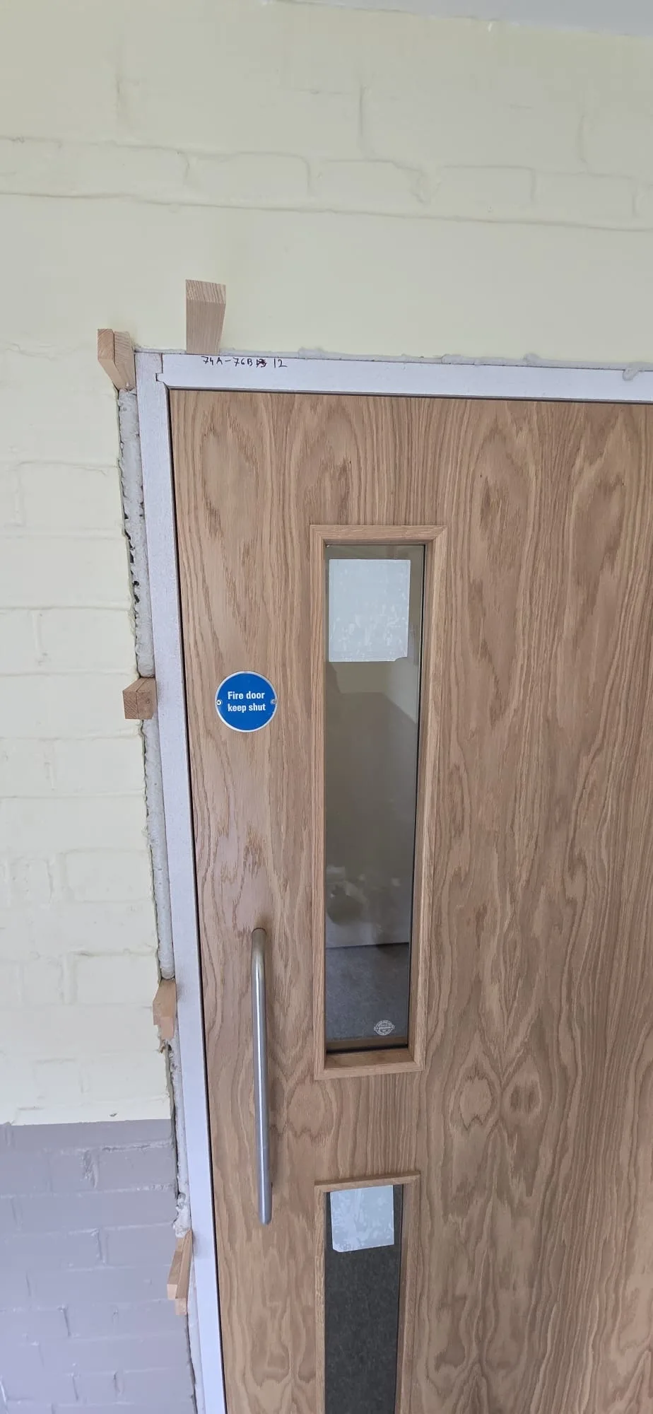 Fire door installation with visible frame and window panes, ready for final touch-ups