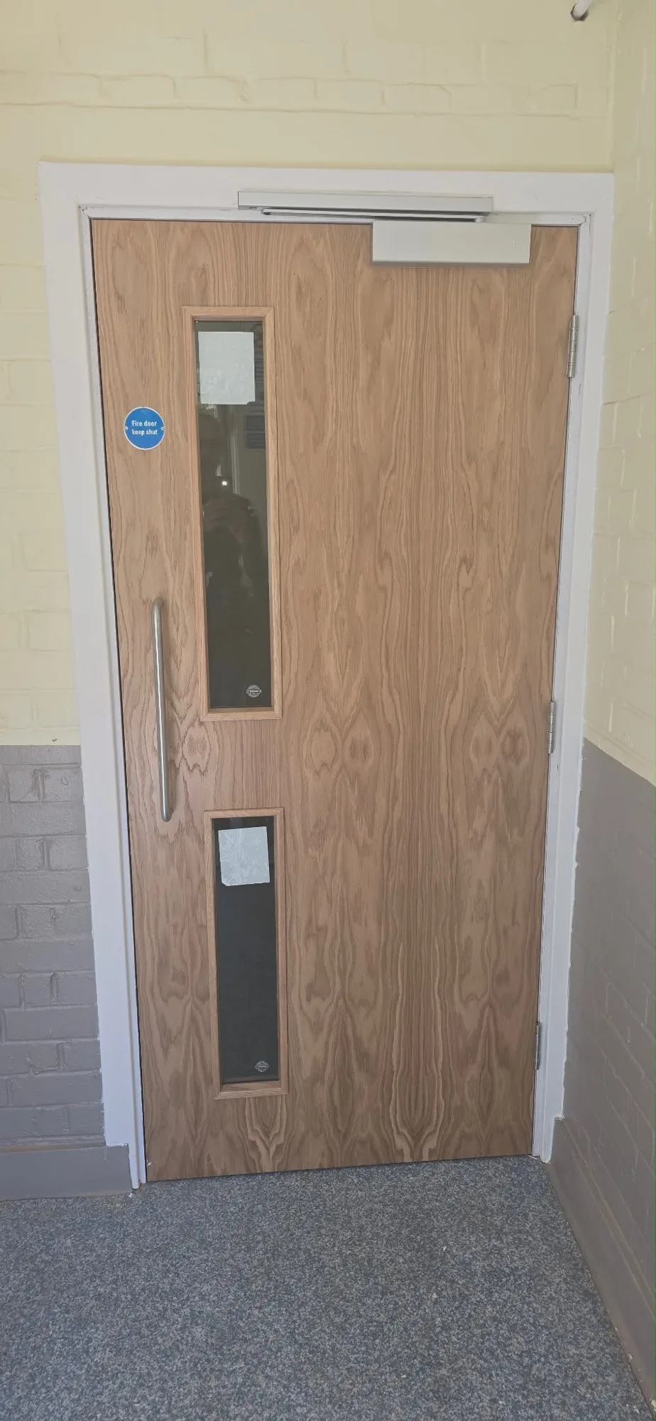 Fire door installation with glass panels in a corridor setting