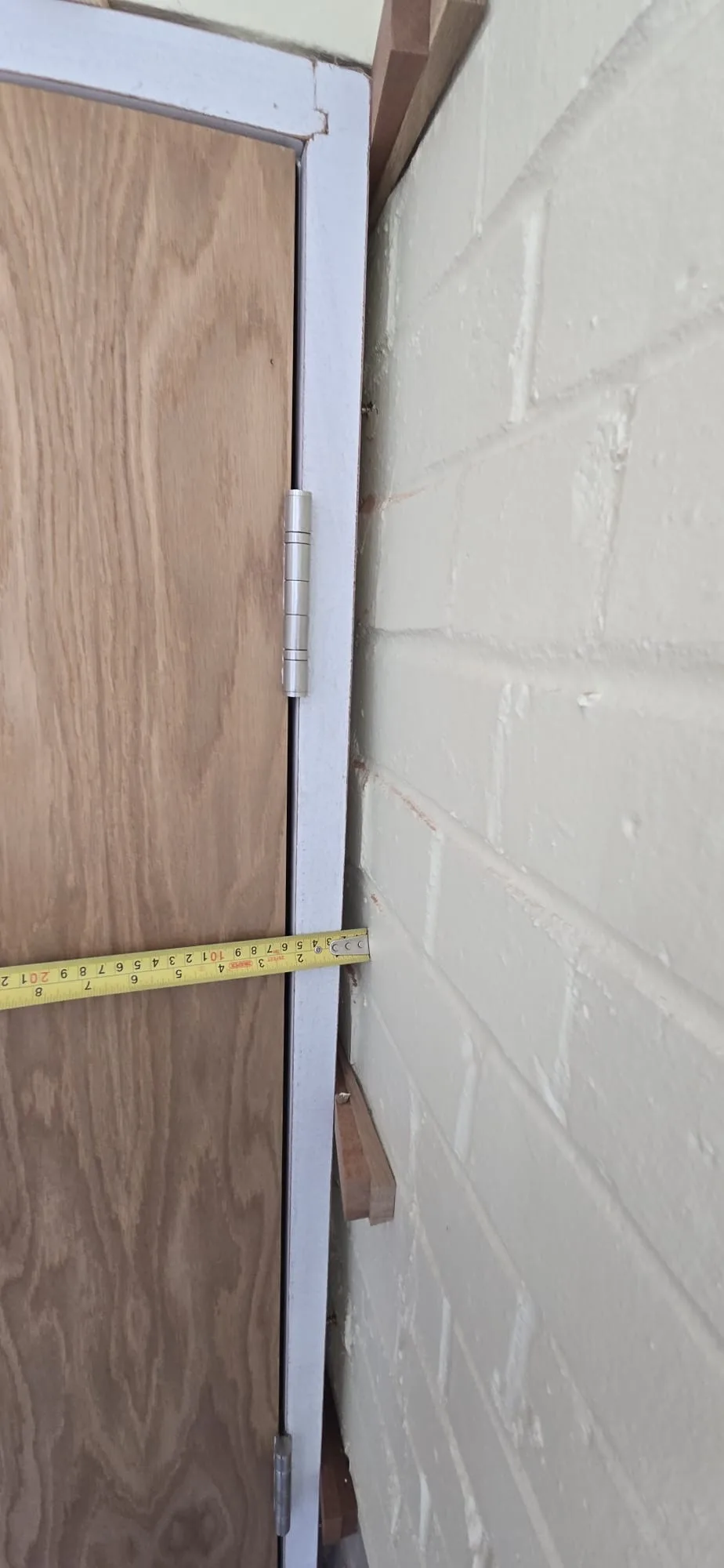Wooden fire door installation with measuring tape displayed for precise fitting
