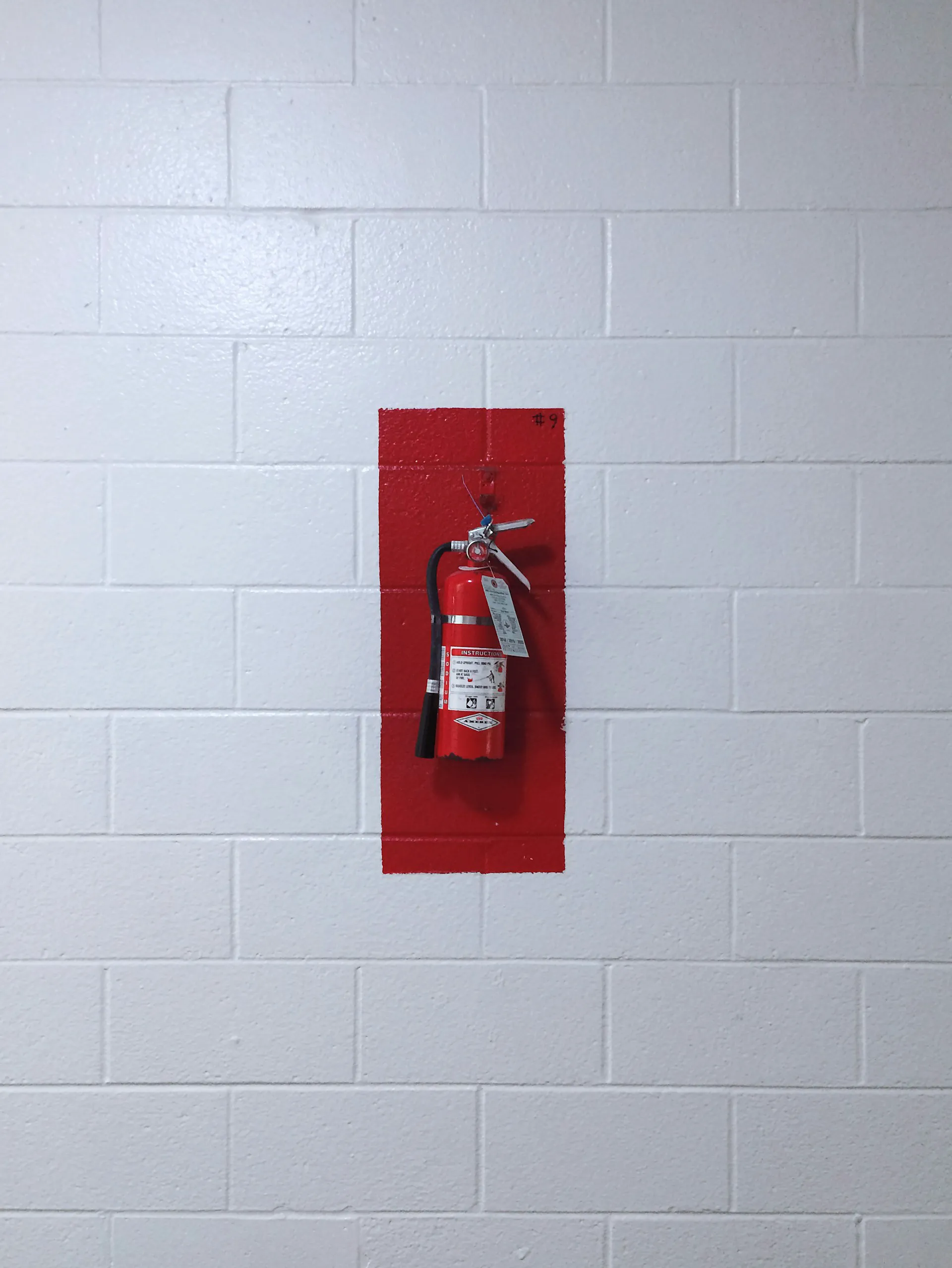 A fire extinguisher mounted on a red-painted wall, demonstrating fire safety equipment